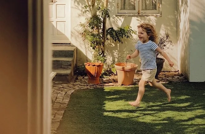 Enfant courant dans un jardin au soleil